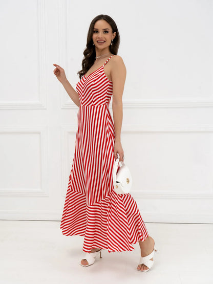 Model wearing a striped red-and-white maxi dress with chevron design and a tiered hem, accessorized with a white bag.