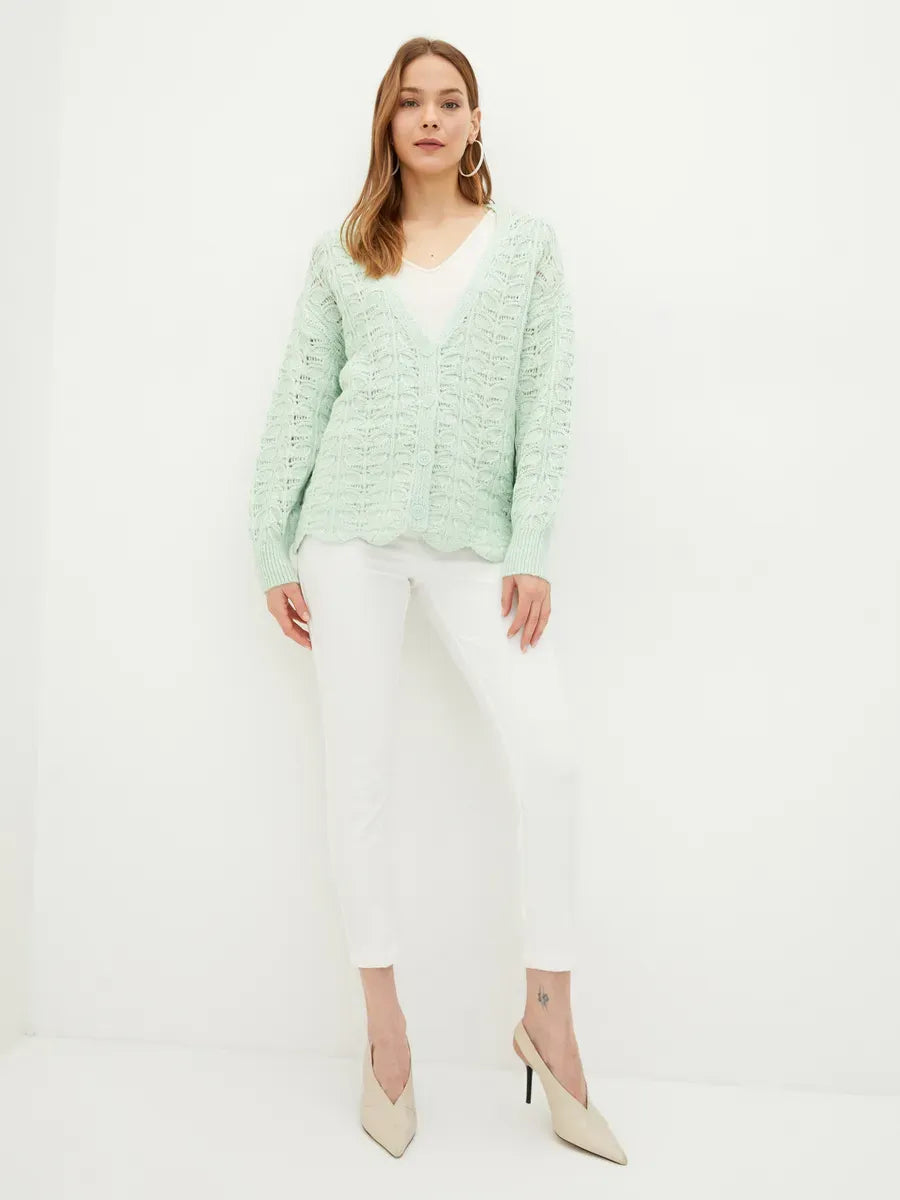 Celestia Cardigan by Lauven featuring a soft green jacquard knit design, styled with white pants and heels.