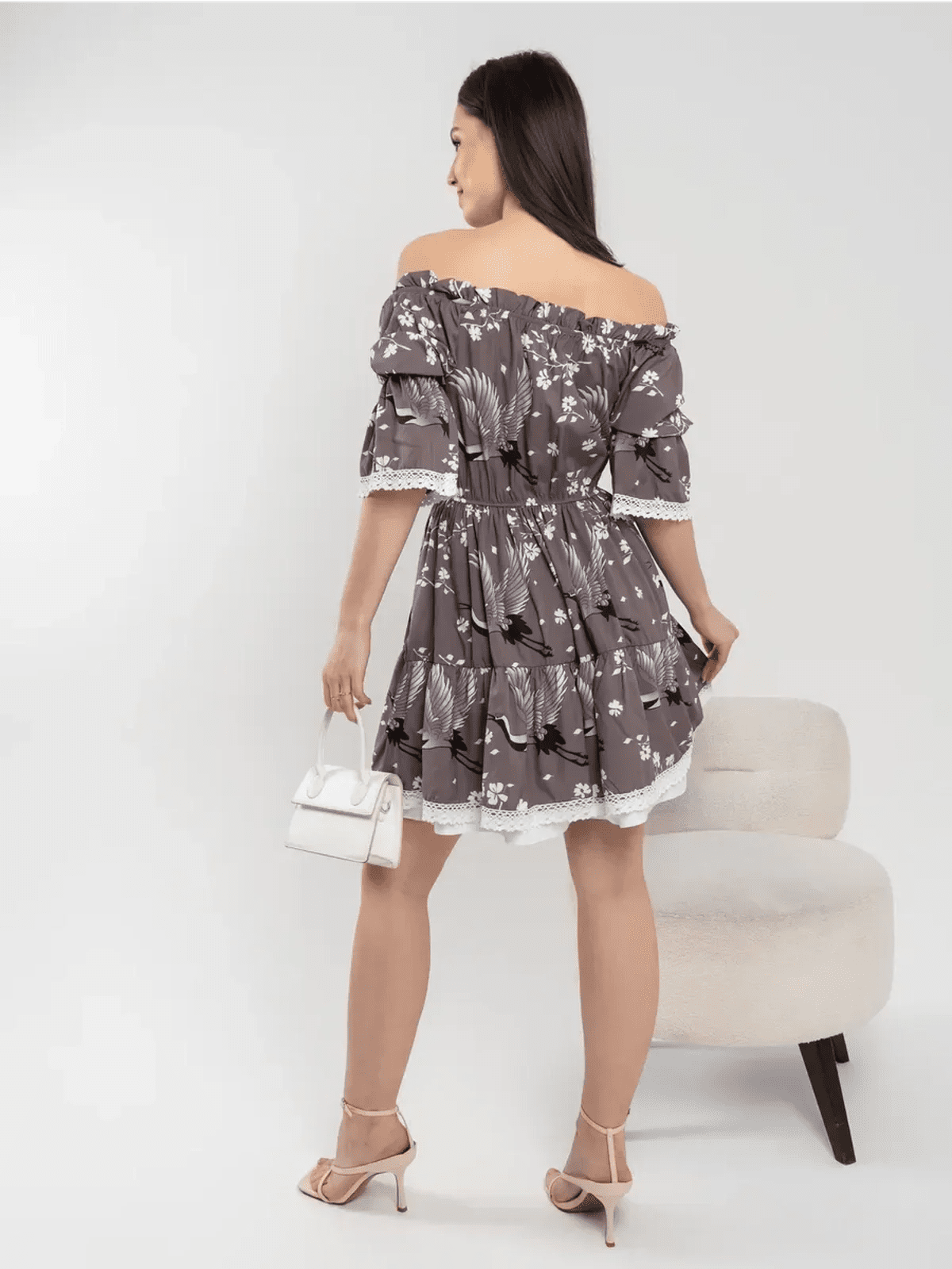 Back view of a woman in a grey-brown off-shoulder mini dress with cranes and cherry blossoms.