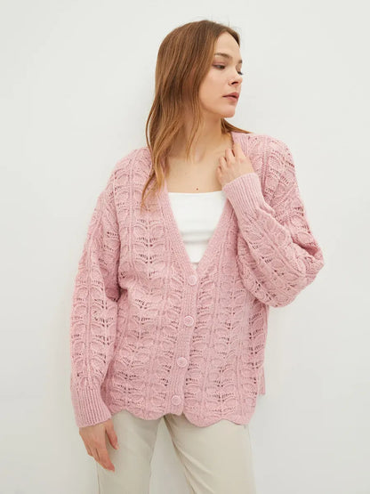 A model wearing the Liora Cardigan by Lauven in soft pink, showcasing its delicate jacquard knit and V-neckline.