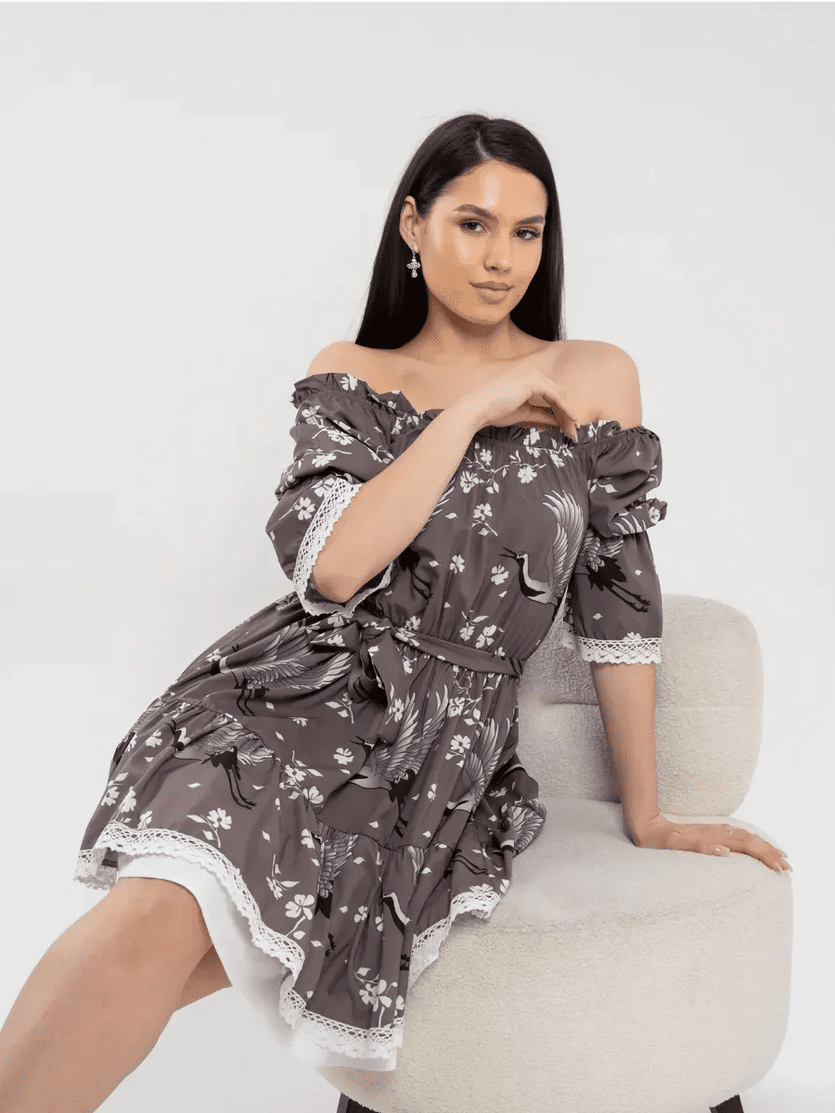 Model showcasing the Sakura Flight off-shoulder mini dress in grey-brown with cherry blossoms and cranes, radiating feminine charm.