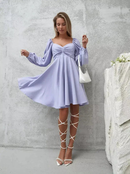 Lilac mini dress with voluminous sleeves and ruched bust, paired with elegant lace-up heels and a stylish handbag.