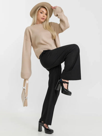 Woman wearing Siena Sweater by Lauven, beige knitwear paired with black pants and heels, showcasing effortless style.