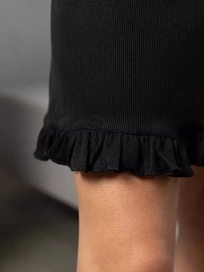 Close-up of the ruffled hem of the Noir Flare black mini dress showcasing its ribbed texture and elegant detail.