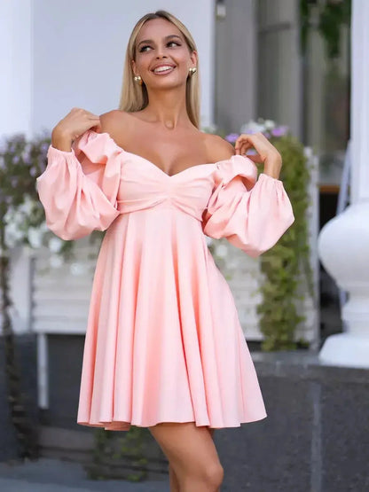 Model wearing a peach-pink mini dress with voluminous sleeves and a flattering neckline, perfect for summer occasions.