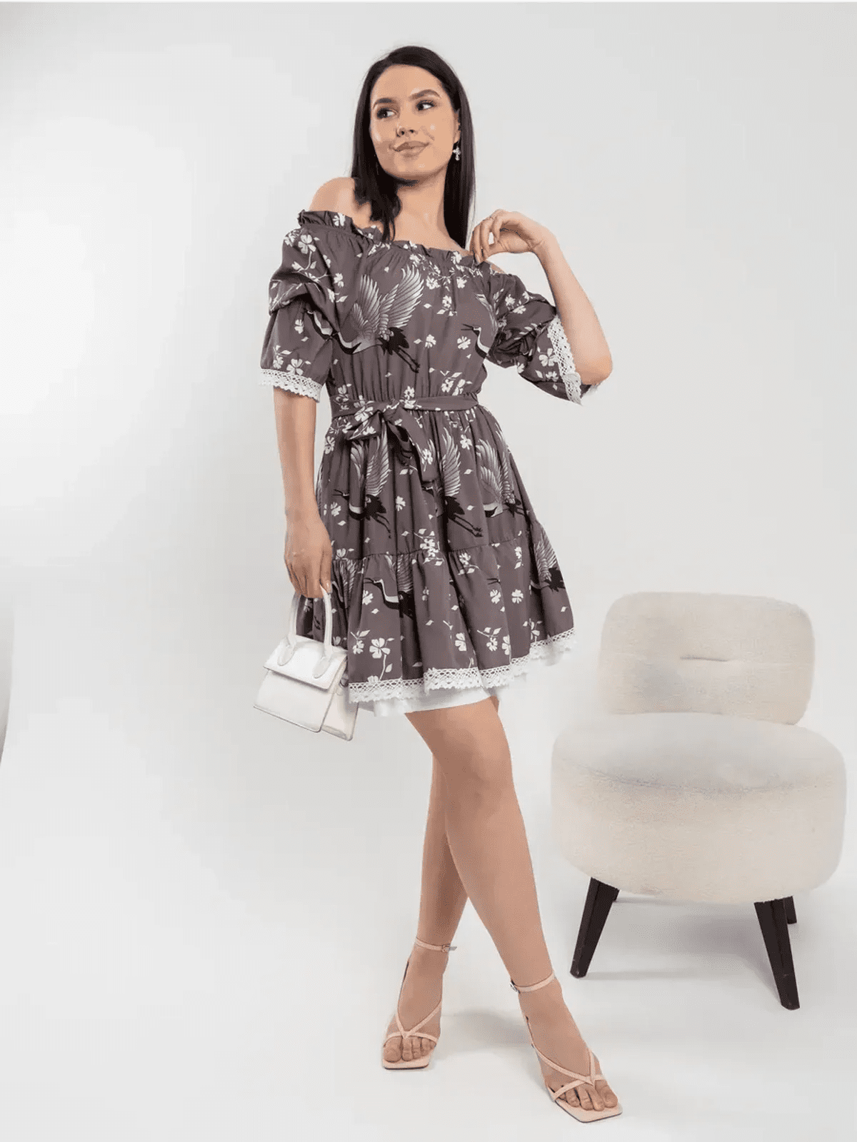 Woman in a grey-brown off-shoulder dress with cherry blossoms and cranes, showcasing grace and femininity.