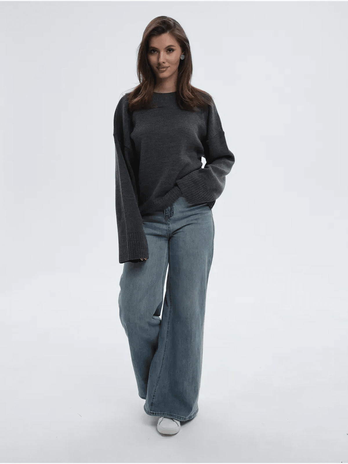 Woman wearing Aria Sweater in anthracite gray with wide-leg jeans, showcasing a stylish oversized knit look.