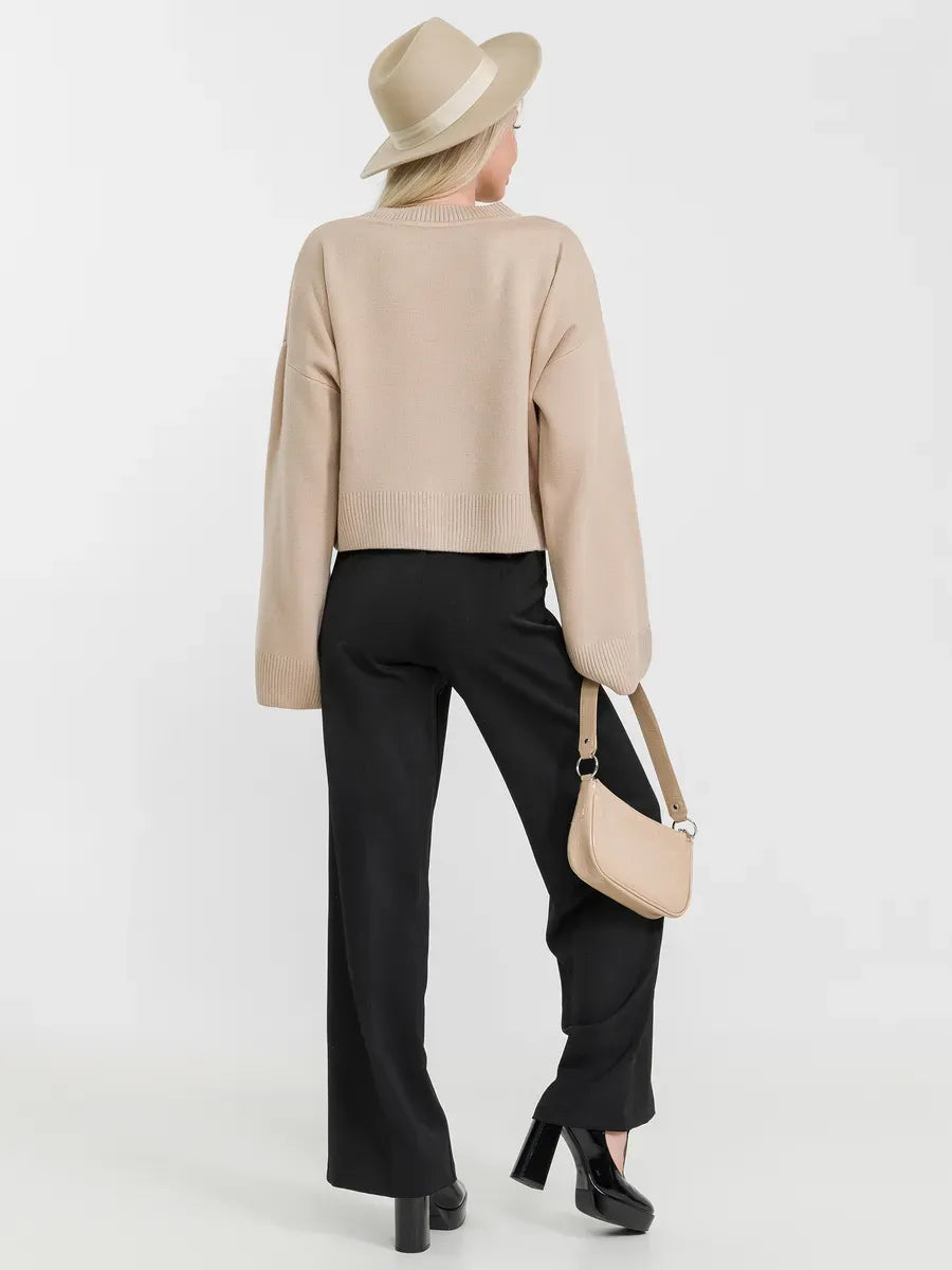 Siena Sweater by Lauven in soft beige, paired with black pants and a stylish hat, showcasing effortless chic.