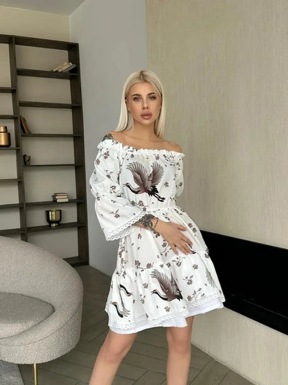 Model in a white crane print mini dress with long sleeves, showcasing summer elegance and modern artistry.