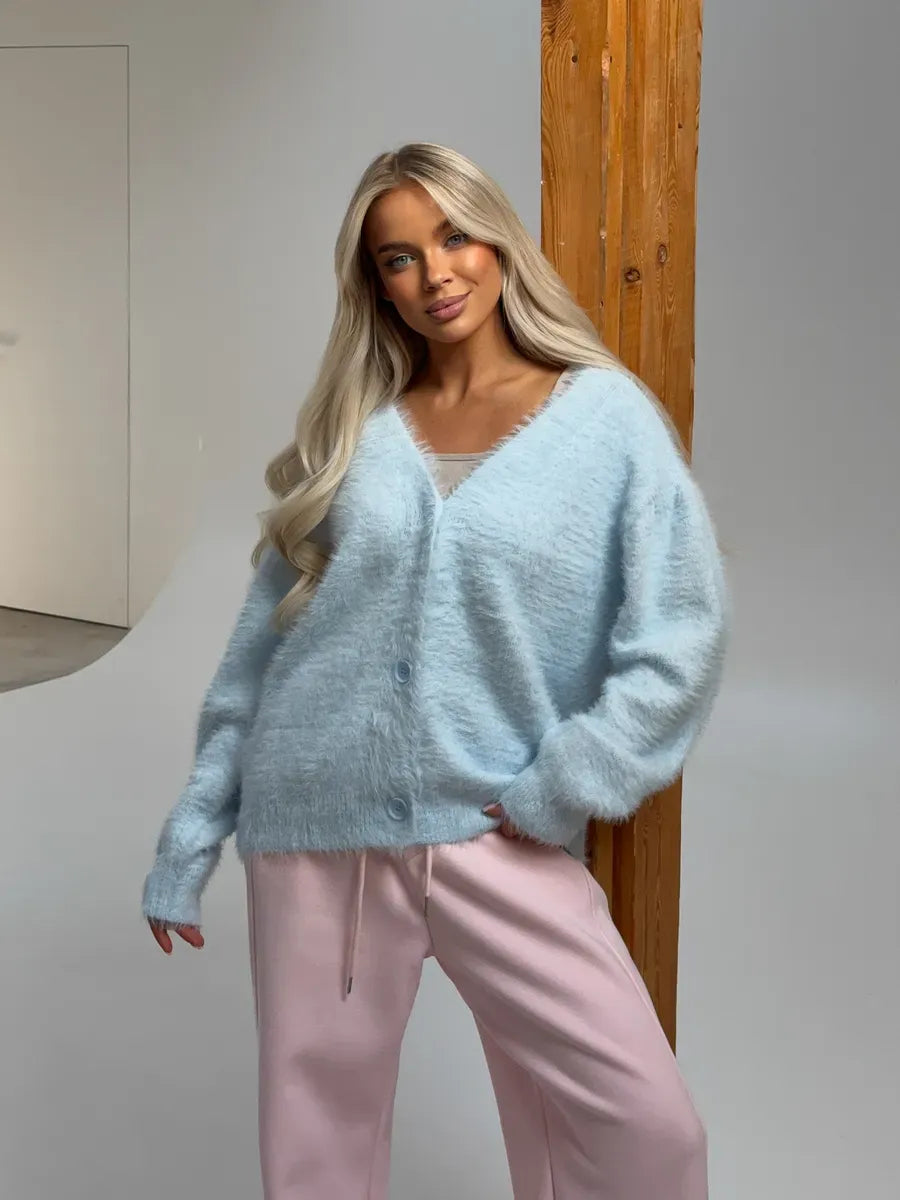 Model wearing an Azure Cardigan by Lauven in oversized light blue fluffy knit with button closure.