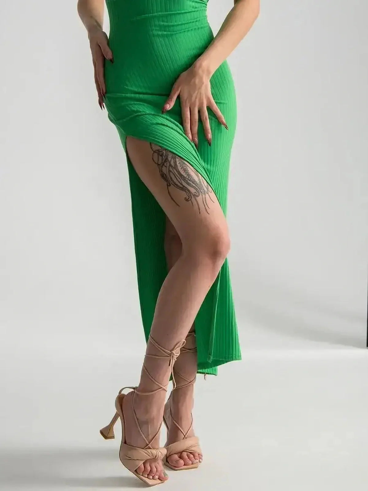 Model showcases the Maxi Dress Emerald Whisper with a bold leg slit and strappy back, epitomizing contemporary elegance.