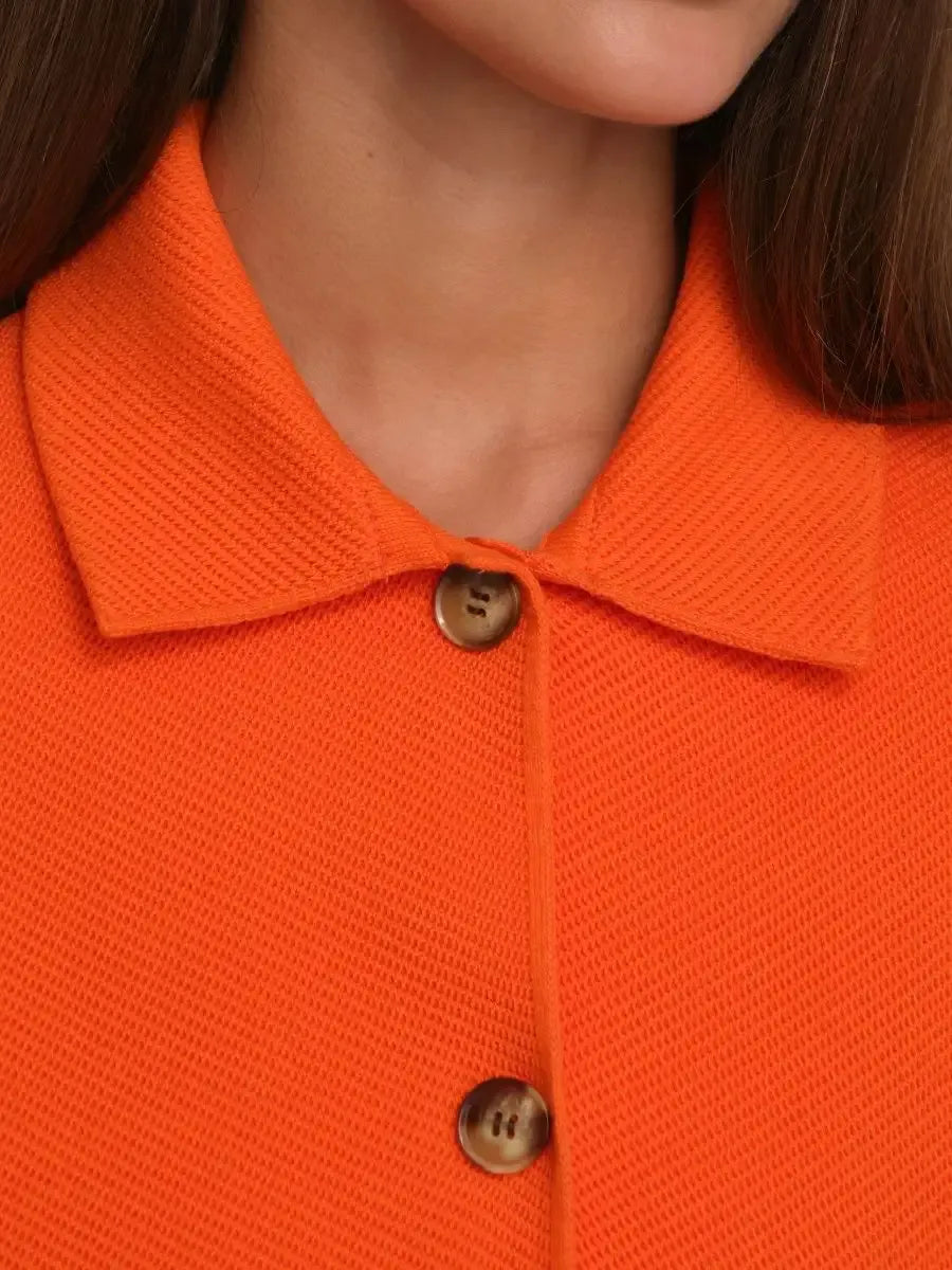 Close-up of Coral Jacket collar with button details, vibrant orange color by Lauven, showcasing modern style.