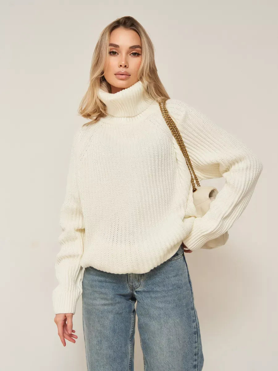 Model wearing the Luna Sweater by Lauven, an oversized white knitwear with a turtleneck and casual jeans.
