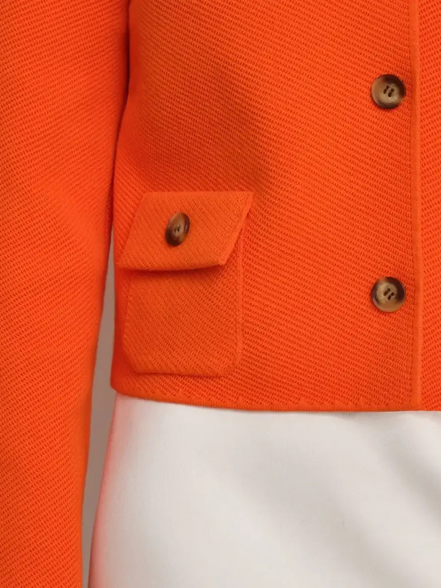 Close-up of the Coral Jacket by Lauven, featuring a cropped design and button closure in bold orange fabric.