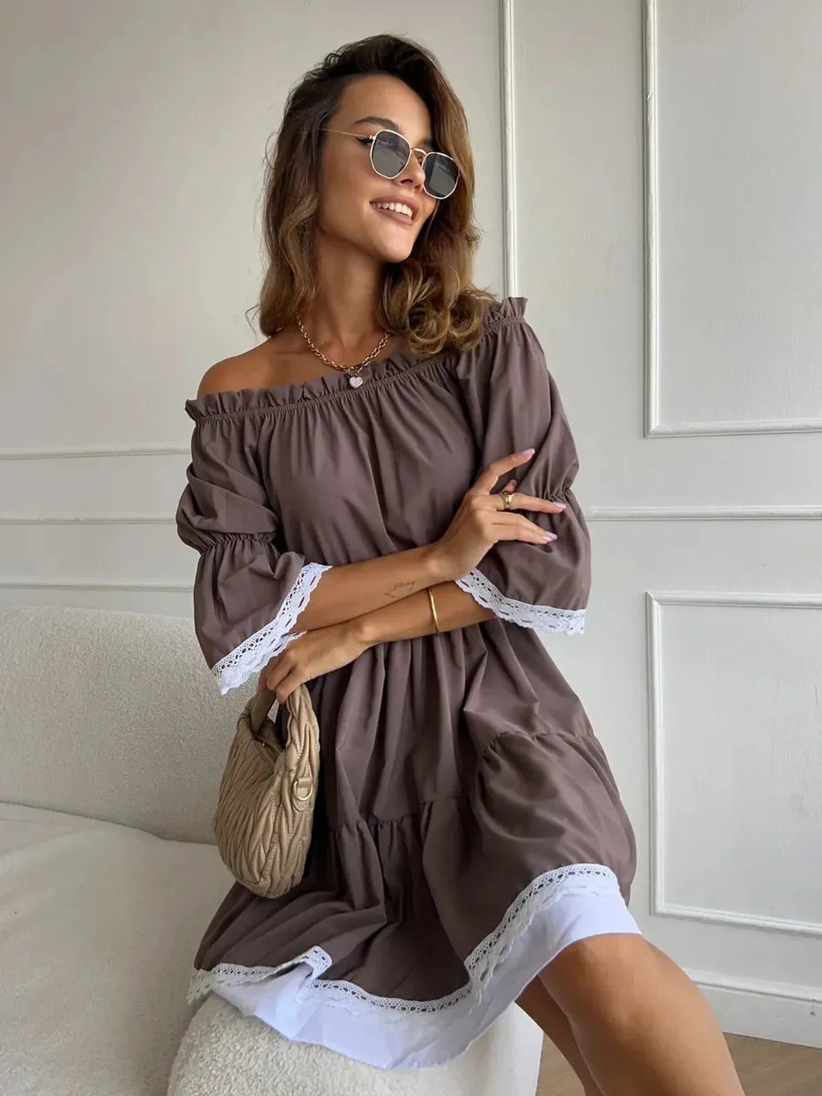 Woman wearing a mocha brown off-shoulder mini dress with ruffle trim, exuding summer charm and elegance.