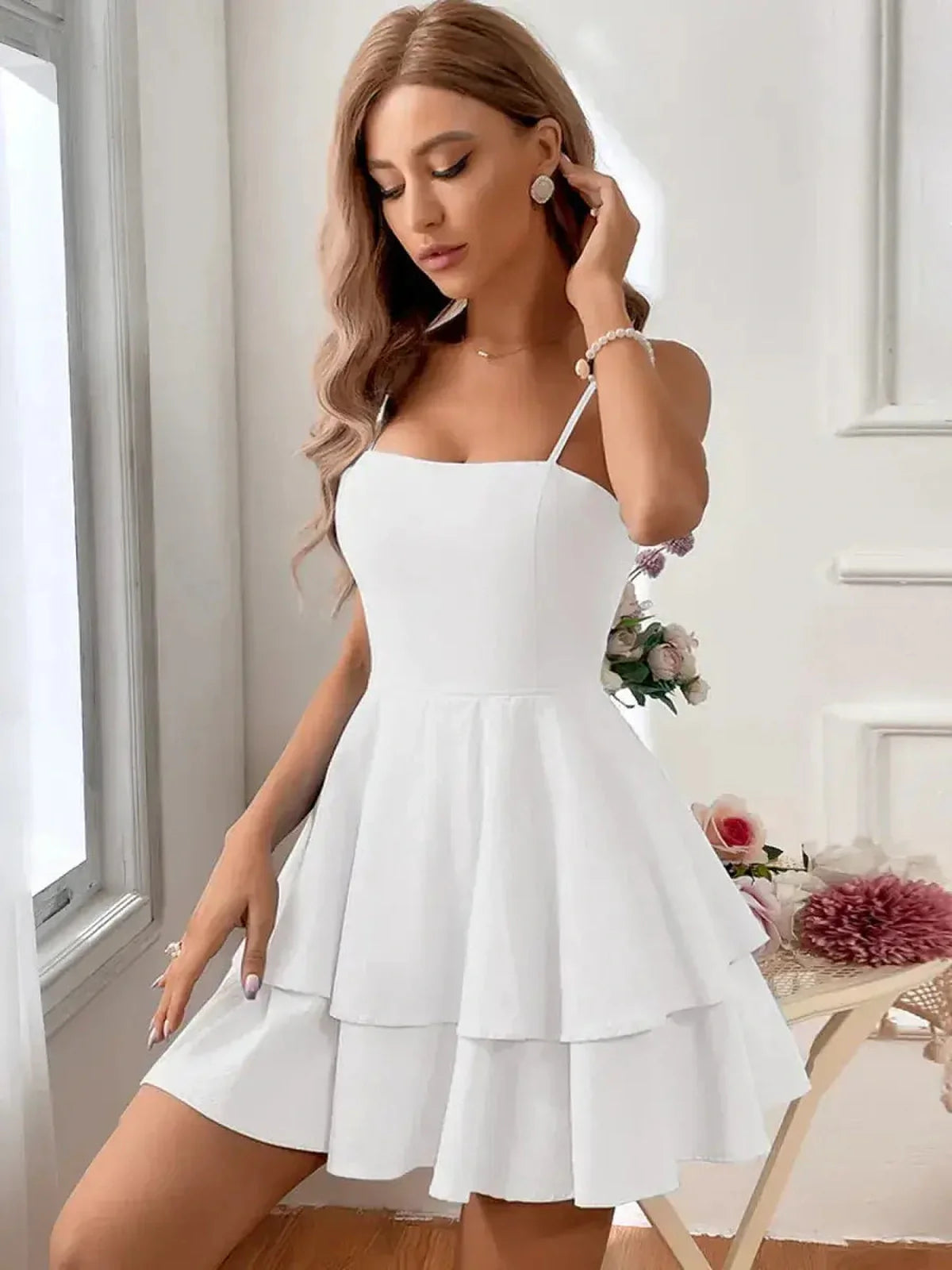 White crinkled cotton mini dress with tiered skirt and back bow, perfect for summer occasions.