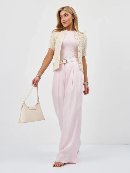 Woman wearing a lightweight Lumiere Cardigan over a pink outfit, showcasing Lauven's stylish knitwear.