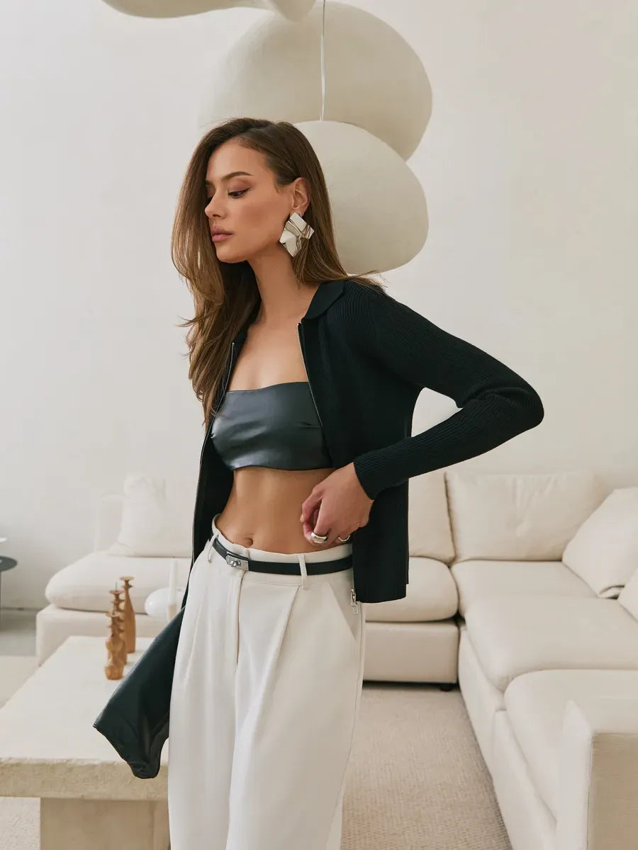 Elegant woman wearing a Nova Cardigan by Lauven, showcasing a black ribbed knit with a two-way zipper and cropped fit.