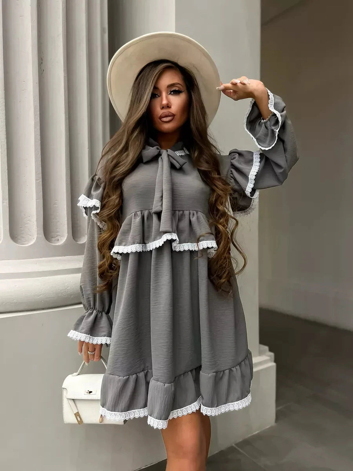 Luna Mini Dress by Lauven featuring an elegant ruffled design and lace trim, styled with a fashionable hat.