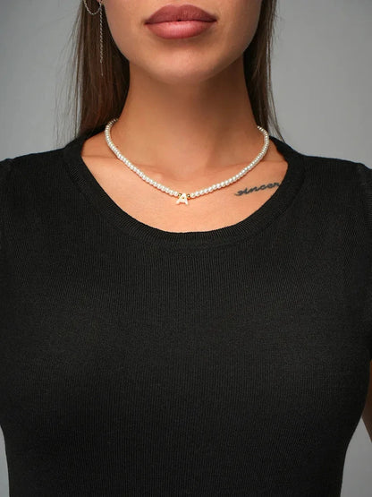 Close-up of woman wearing pearl necklace and black knit top, showcasing elegant style with the Velora Midi Dress.