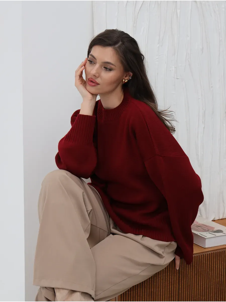 Valora Sweater by Lauven, oversized knit in burgundy red, worn by a model sitting casually.