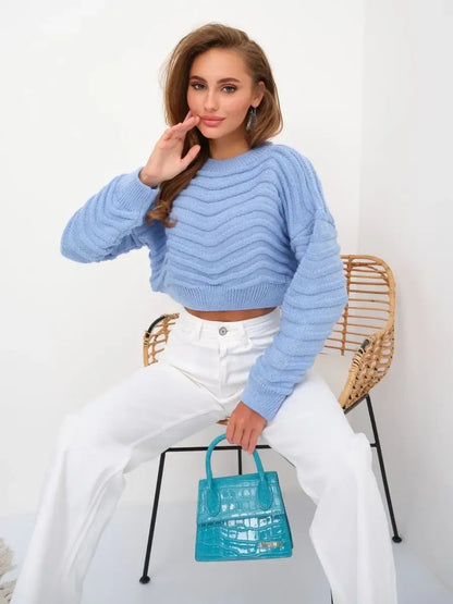 Celeste Sweater by Lauven in sky blue, featuring a textured wave-knit pattern, worn with white pants and a turquoise bag.