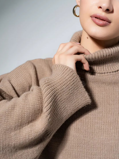 Close-up of a model wearing a Lauven Capri Sweater in cappuccino with a turtleneck collar, showcasing its oversized knit design.