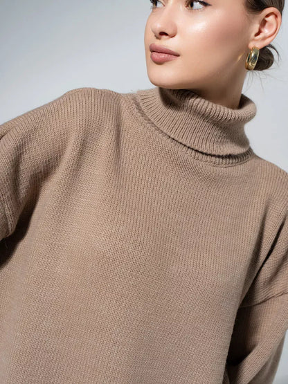 Woman wearing a cozy Capri Sweater in warm cappuccino, showcasing its oversized knit and turtleneck collar by Lauven.