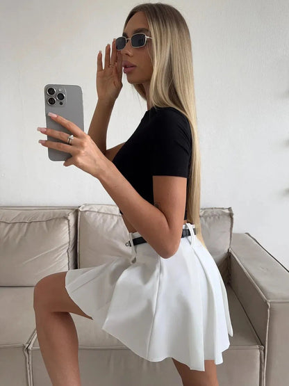 Woman wearing a black top and Capri Mini Skirt, showcasing modern elegance in a stylish pose.