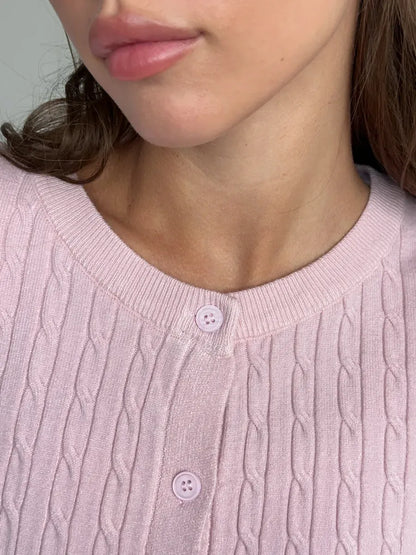 Close-up of a woman wearing the Lauven Rosewood Cardigan with cable knit detail, showcasing its lightweight pink fabric.