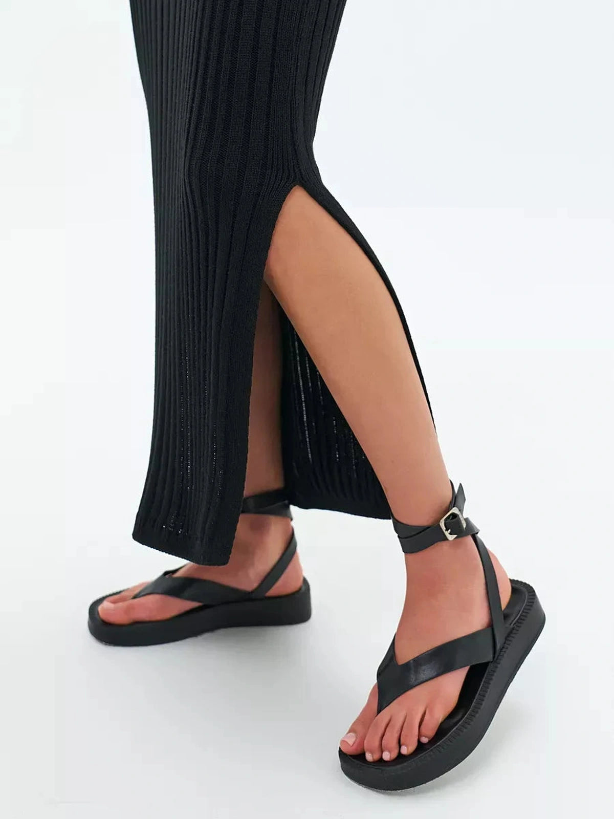 Close-up of leg showcasing black ribbed Noir Midi Dress by Lauven with stylish sandals.