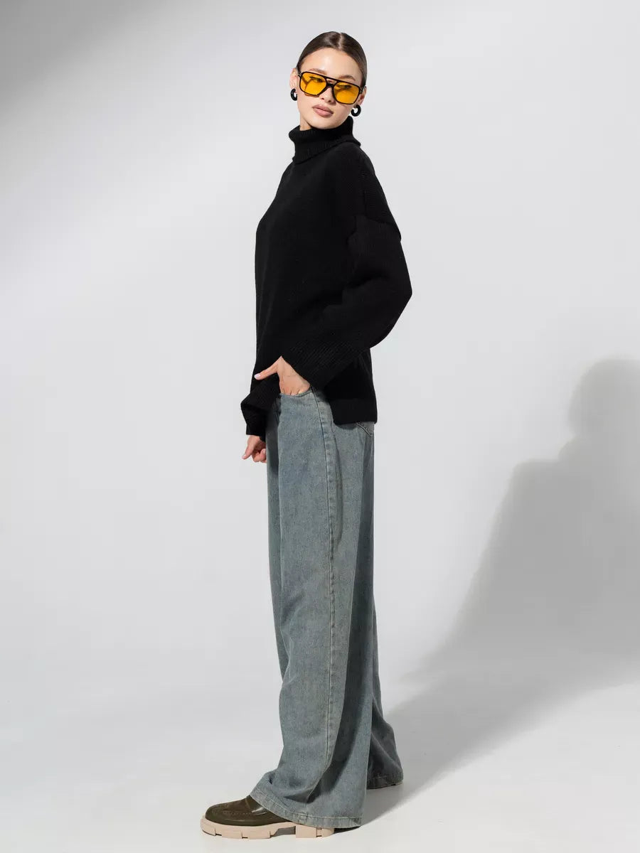 Onyx Sweater by Lauven, an oversized black knit, styled with wide-leg jeans and sunglasses, showcasing elegance and comfort.