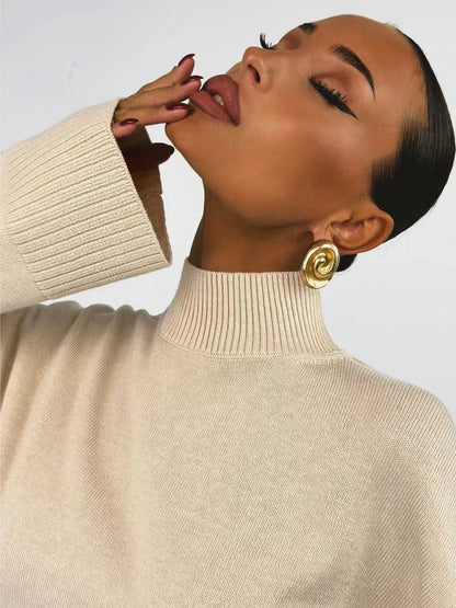 Eterna Sweater by Lauven, oversized light beige knitwear with turtleneck and statement earrings.