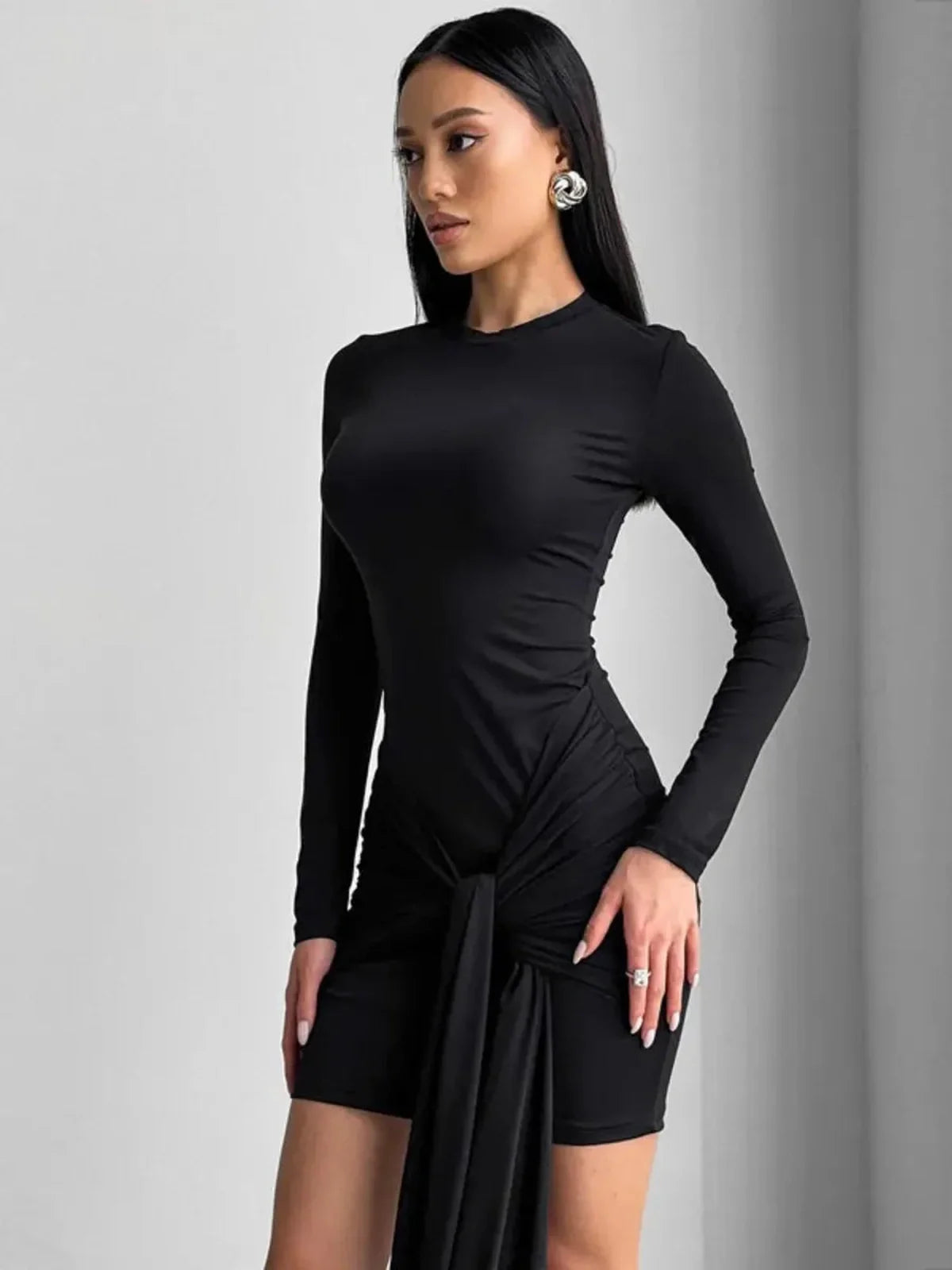 Sleek black mini dress Obsidian Veil with gathered draping and side sash, showcasing sultry elegance and a body-contouring fit.