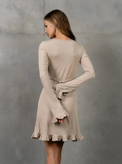 Back view of Luna Flare beige long sleeve dress featuring ruffle accents and adjustable lace-up details.