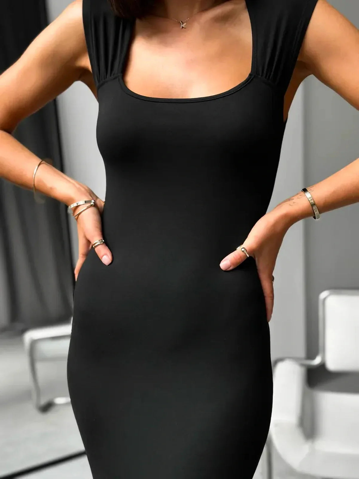 Model showcasing the Sculpted Charm Maxi Dress with a square neckline, highlighting its sleek black fabric and body-hugging fit.