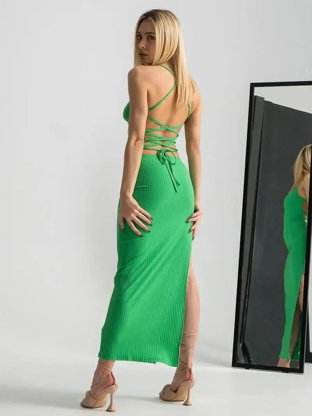 Maxi Dress Emerald Whisper in vibrant green with strappy back and dramatic leg slit, showcased against a mirror.