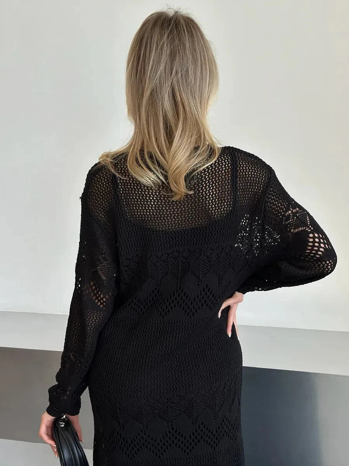 Back view of a woman in a black crochet knitted Lunara Maxi Dress by Lauven, showcasing elegant summer style.