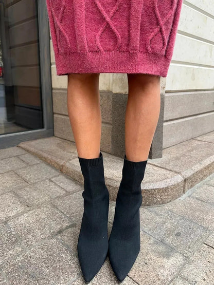 Close-up of legs wearing black sock heels paired with a stylish berry midi dress.