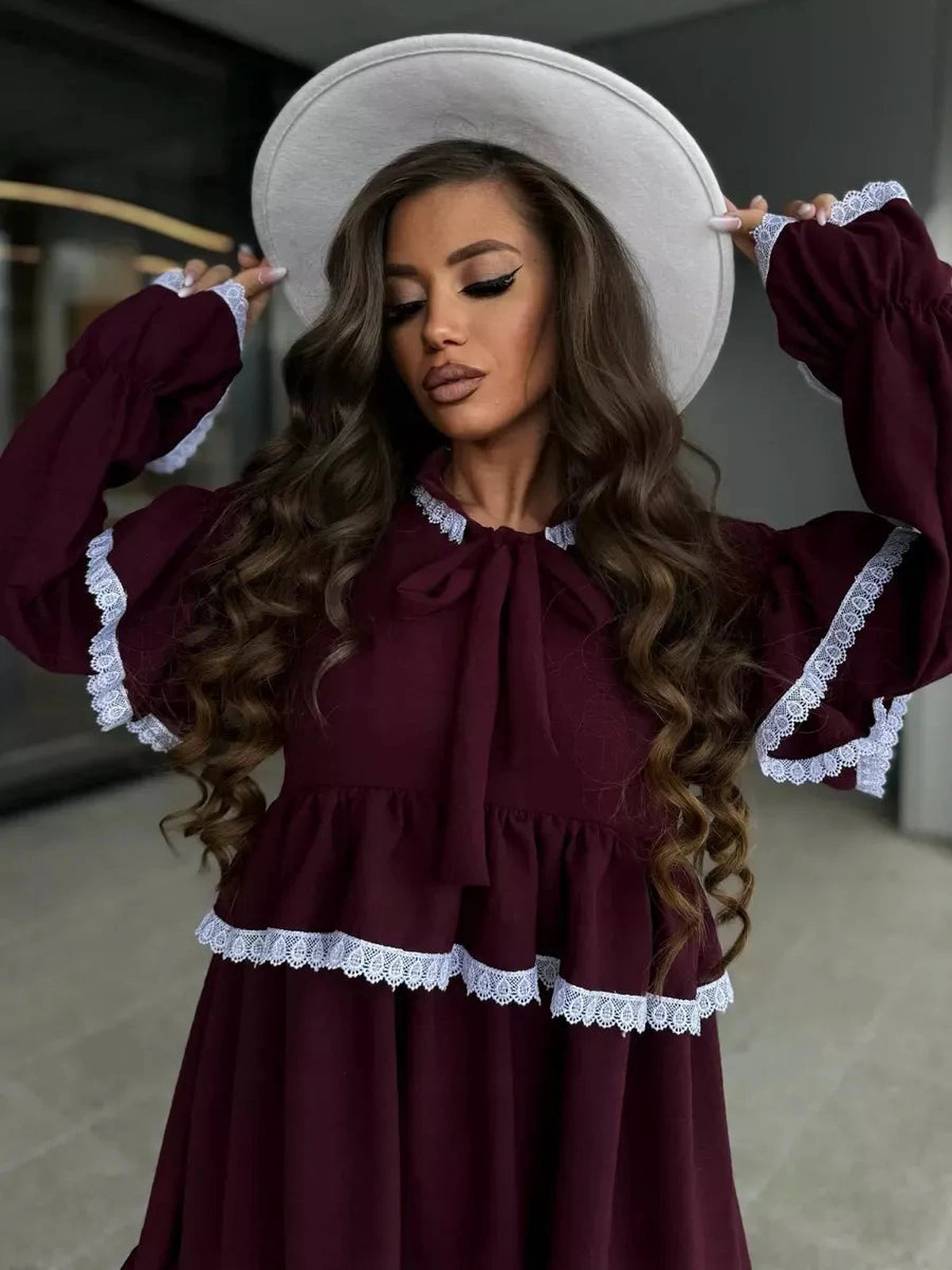 Elegant woman wearing Marina Mini Dress by Lauven, featuring ruffles and lace details in burgundy shade.