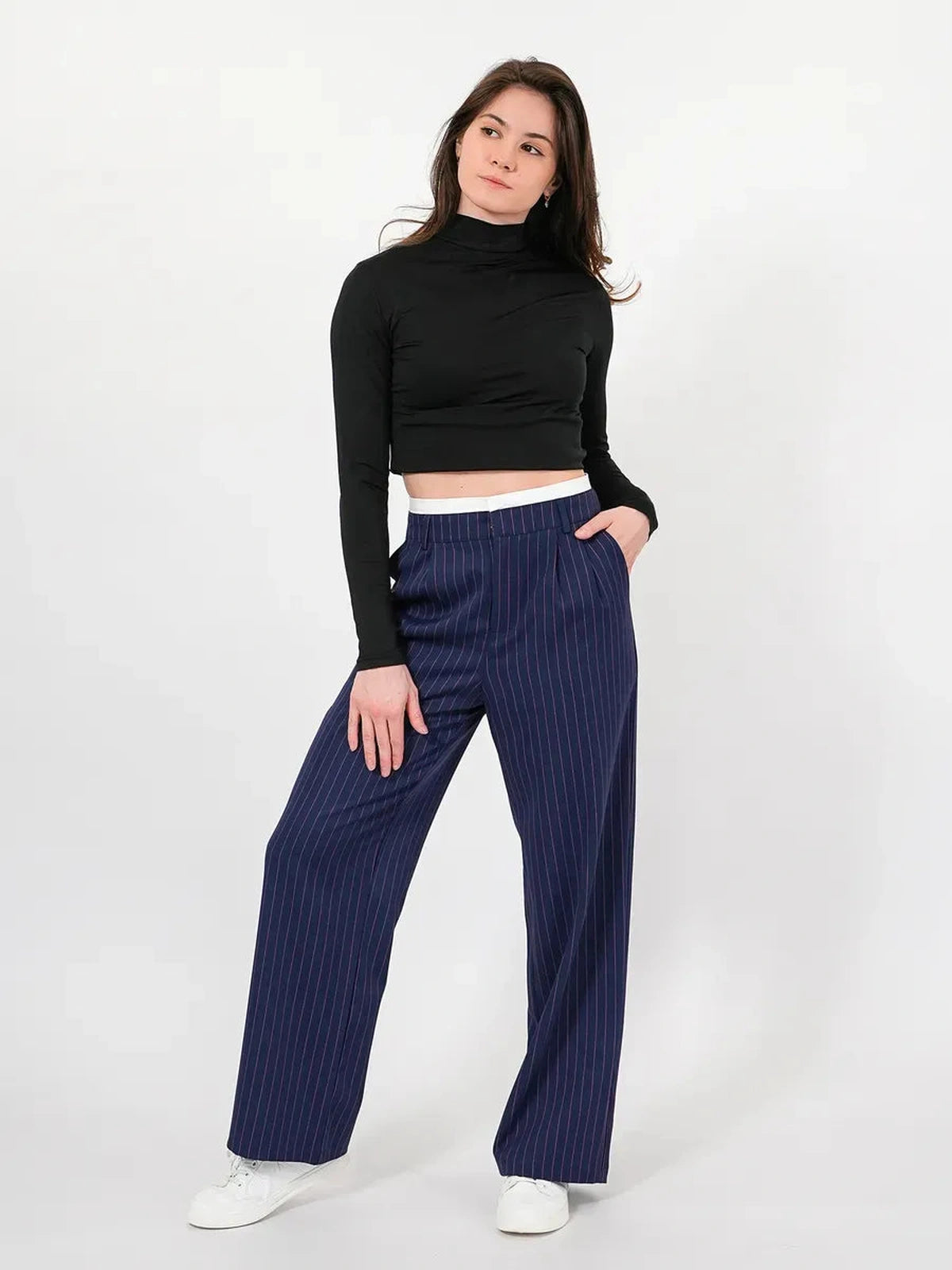 Model wearing Aster Pants with high-waist wide-leg silhouette and pinstripes, from Lauven, styled with a black crop top.
