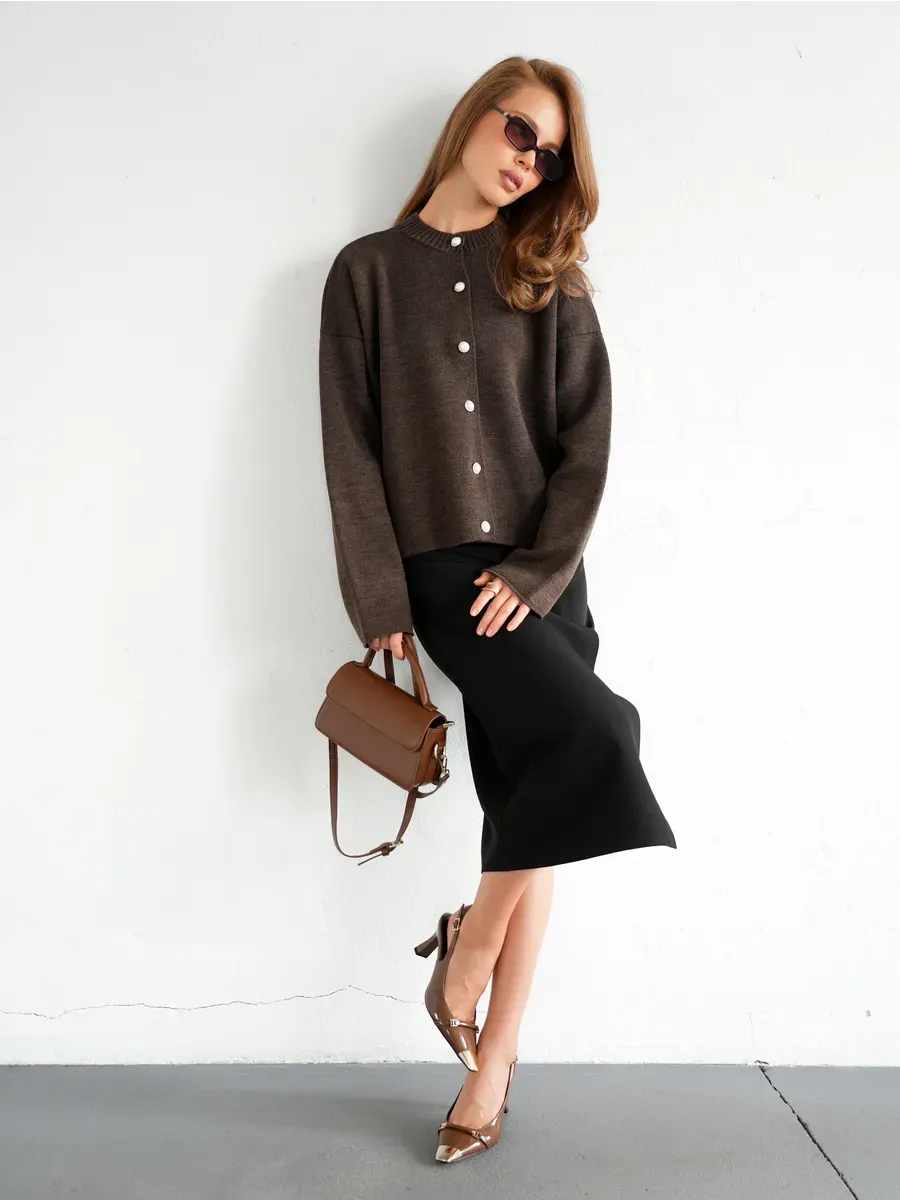 Model showcasing Cocoa Cardigan by Lauven, featuring warm brown knitwear with button closure, paired with a chic skirt.
