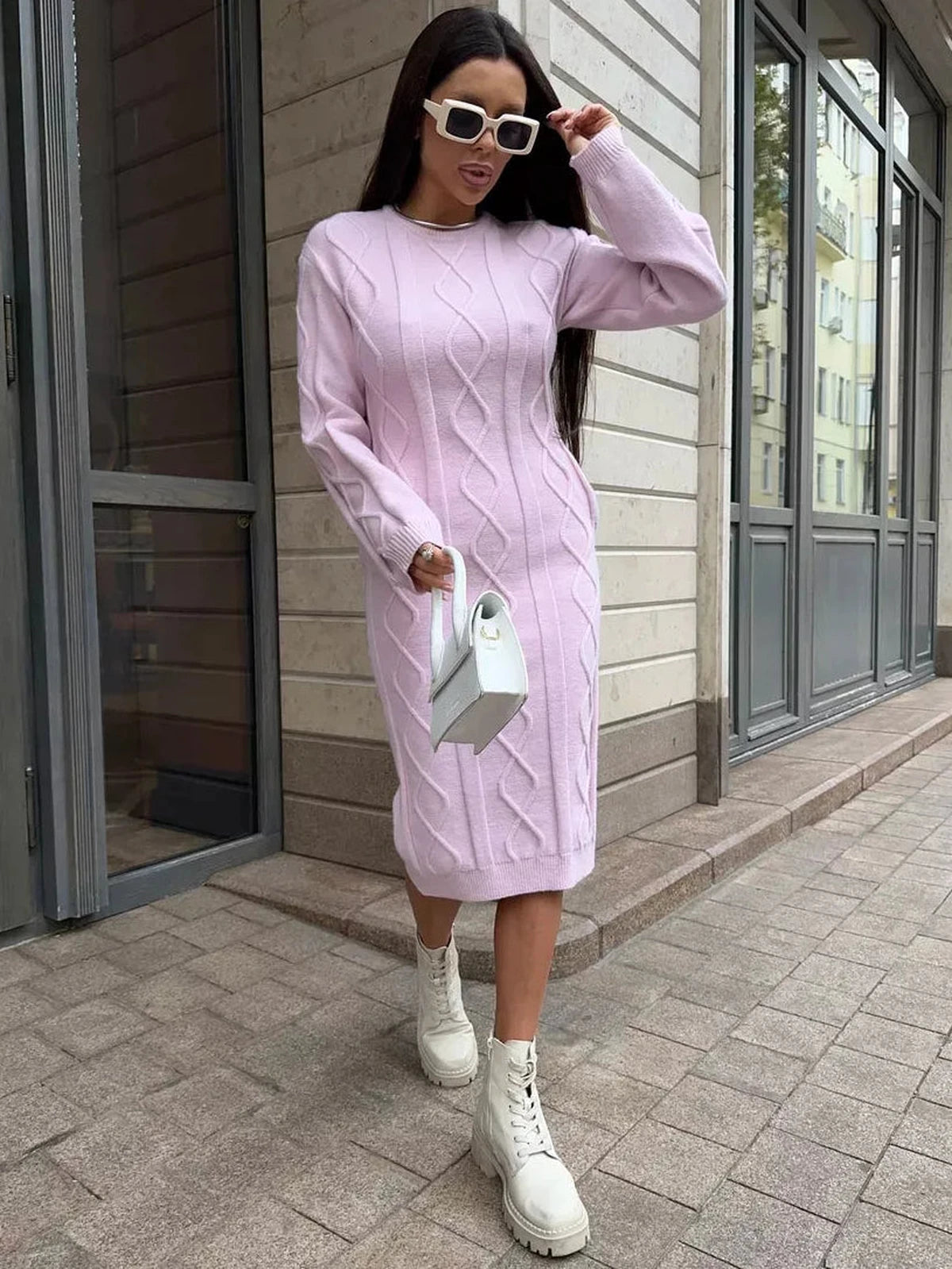 Model wearing the Luna Midi Dress by Lauven, a textured knit sweater dress in soft pink, styled with white boots.