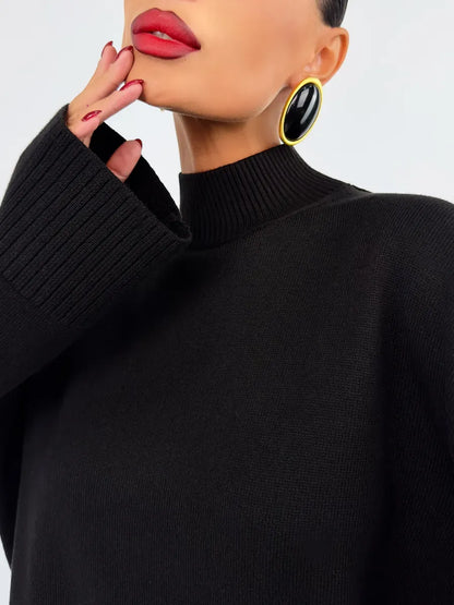 Close-up of a model wearing the Noir Sweater by Lauven, showcasing the oversized black knit and bold earrings.
