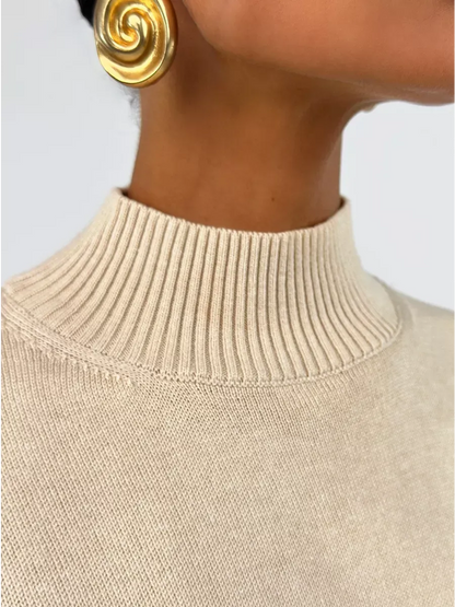 Close-up of Eterna Sweater in light beige with high neck detail, accessorized with statement earrings by Lauven.