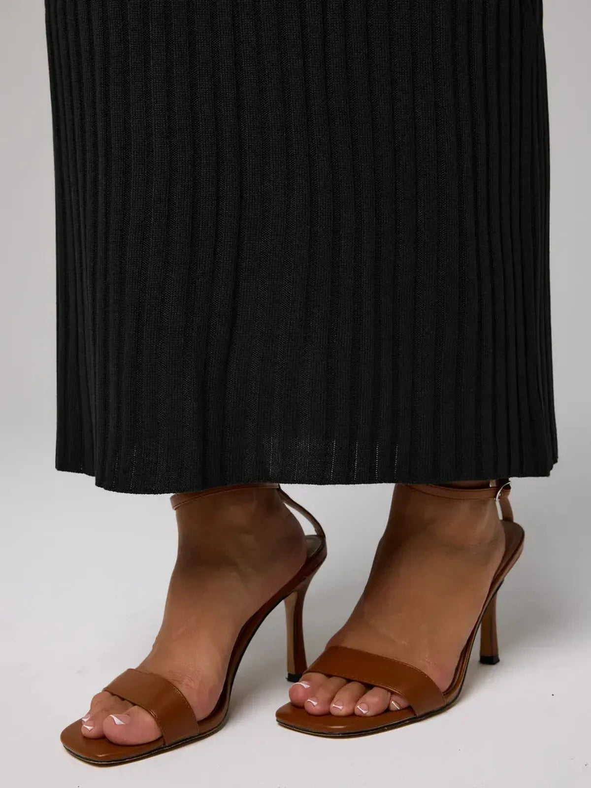 Noir Maxi Dress styled with elegant brown heeled sandals, showcasing sleek black ribbed knit fabric from Lauven.