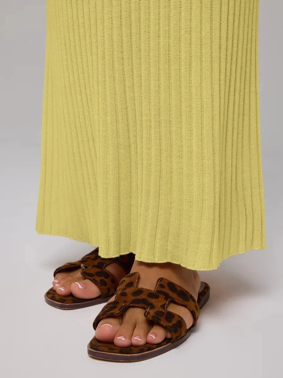 Detail of Soleil Maxi Dress by Lauven, featuring a yellow ribbed knit and stylish leopard print sandals.