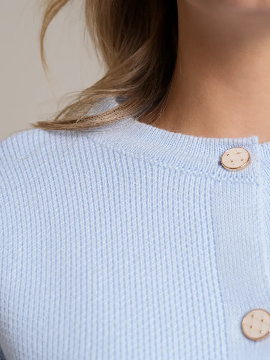 Close-up of the Celeste Cardigan by Lauven in light blue, featuring decorative buttons and soft knit texture.