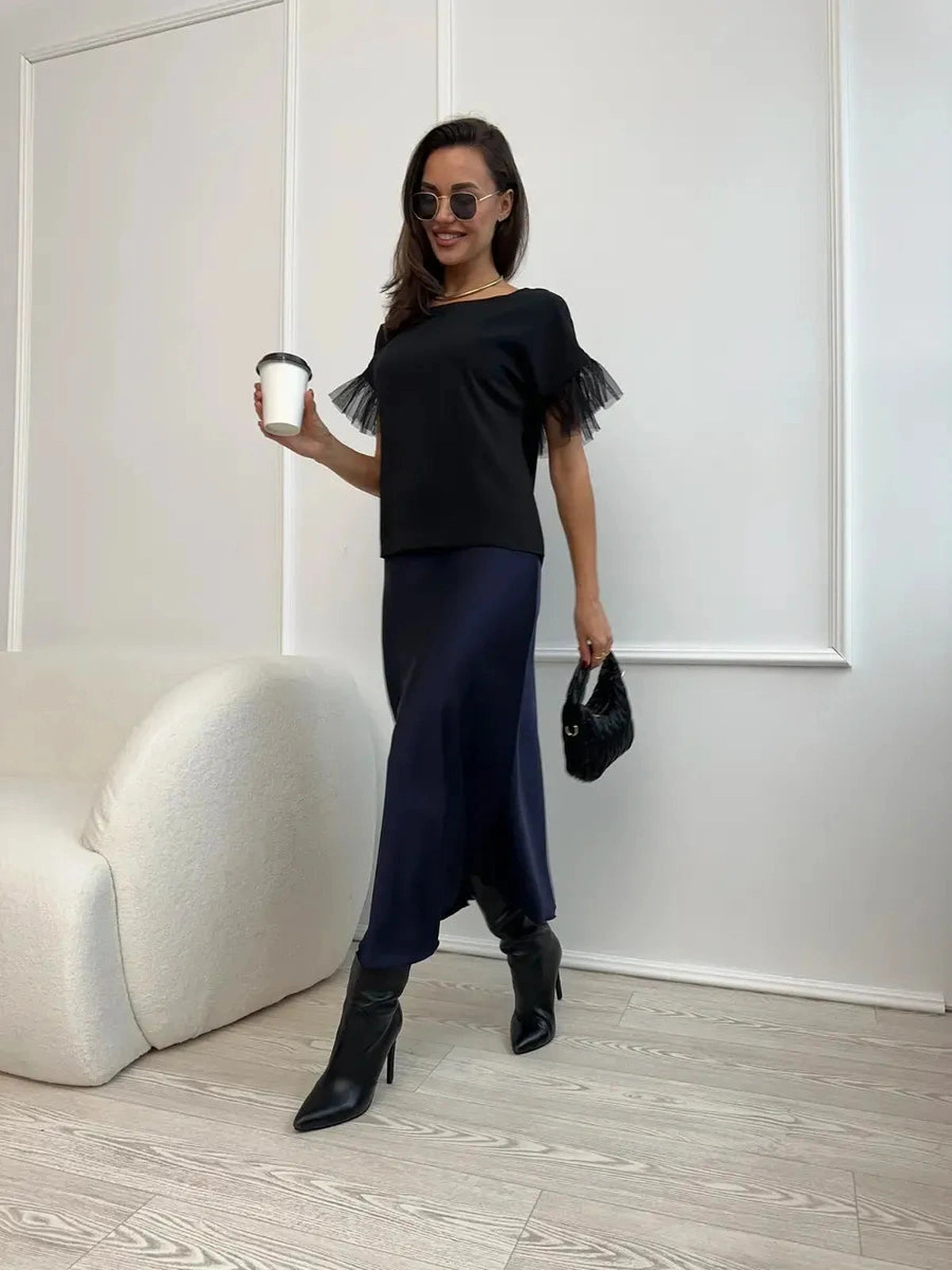 Model wearing the Noiré Blouse by Lauven, featuring short sleeves and tulle ruffle detail, paired with a long skirt.