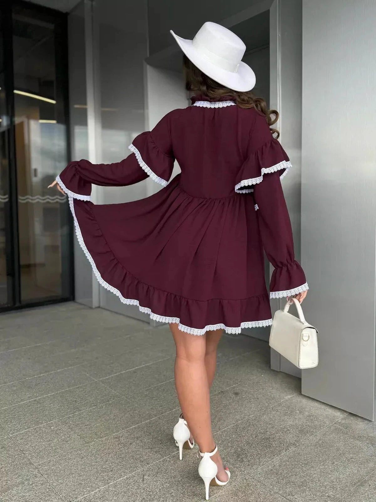 Model showcasing the Marina Mini Dress by Lauven, featuring lace trim and flared sleeves in burgundy.